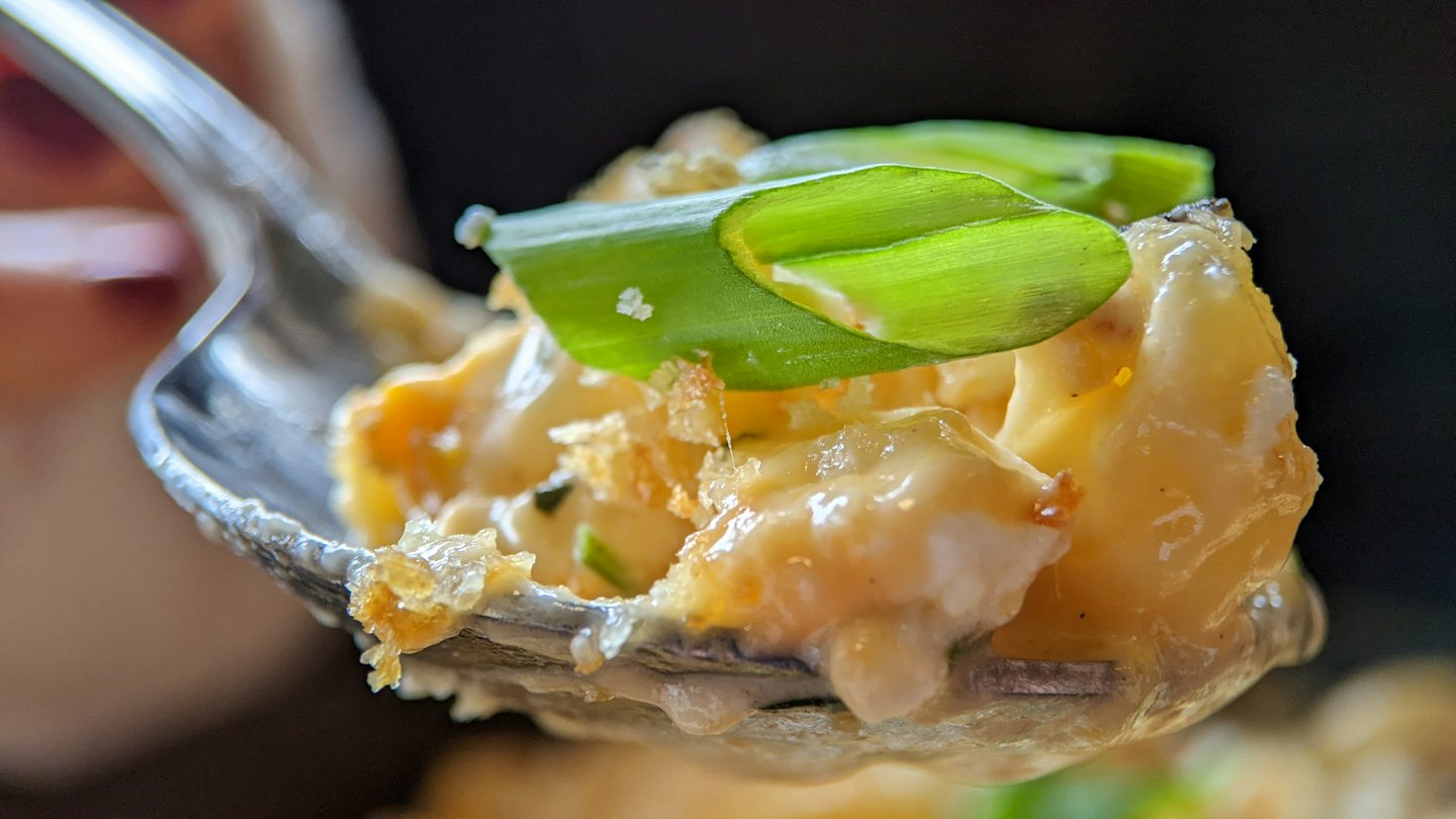A spoon holds a serving of creamy macaroni and cheese.