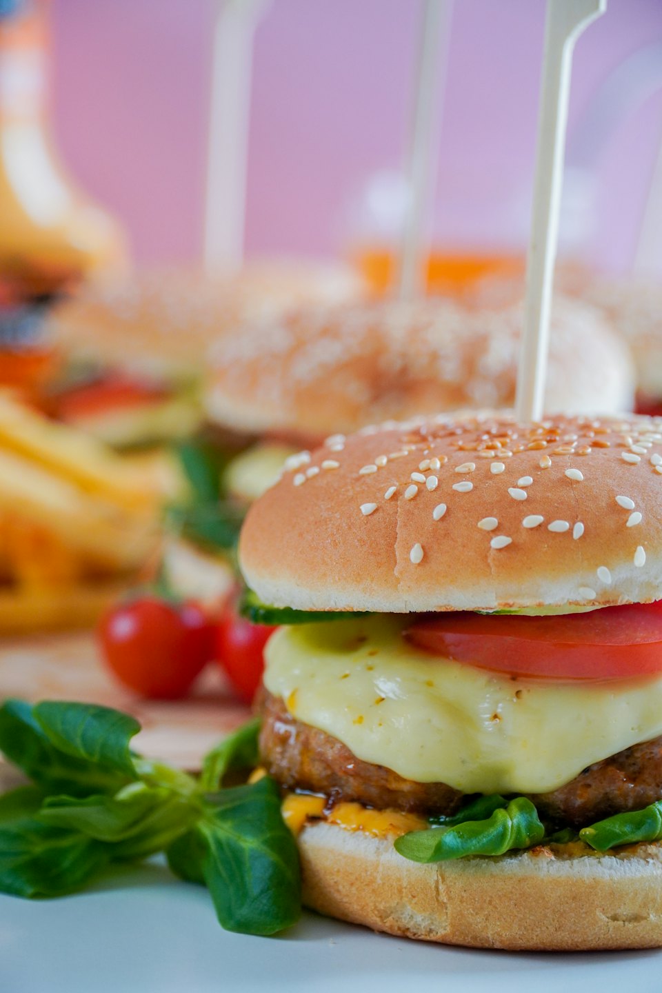 Mini burger with cheese and vegetables on a skewer.