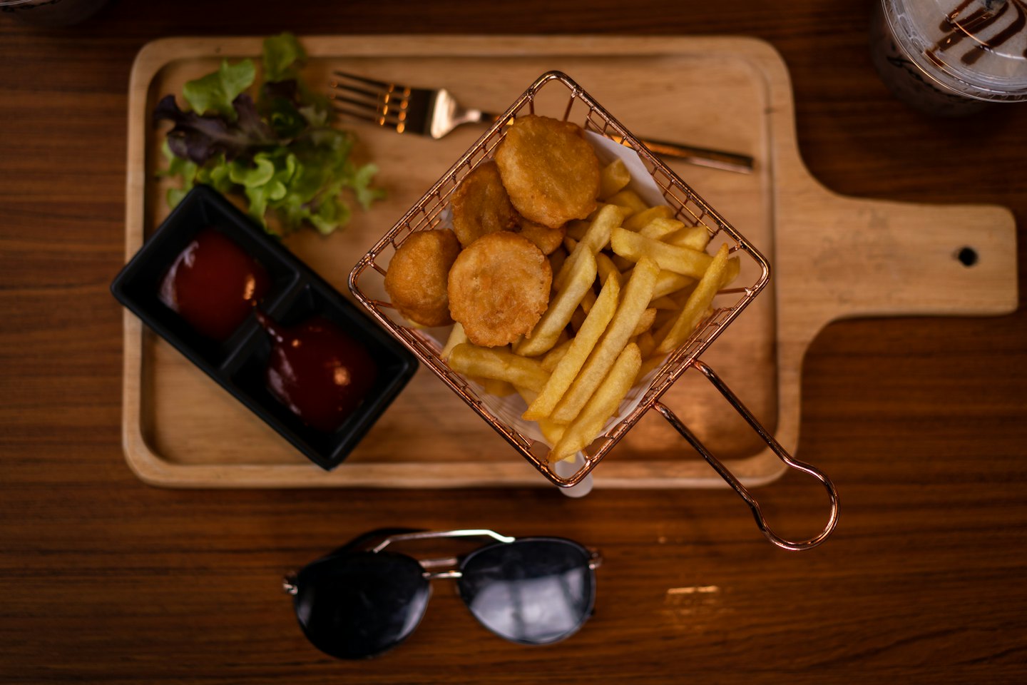 Chicken nuggets and fries served on a wooden board.